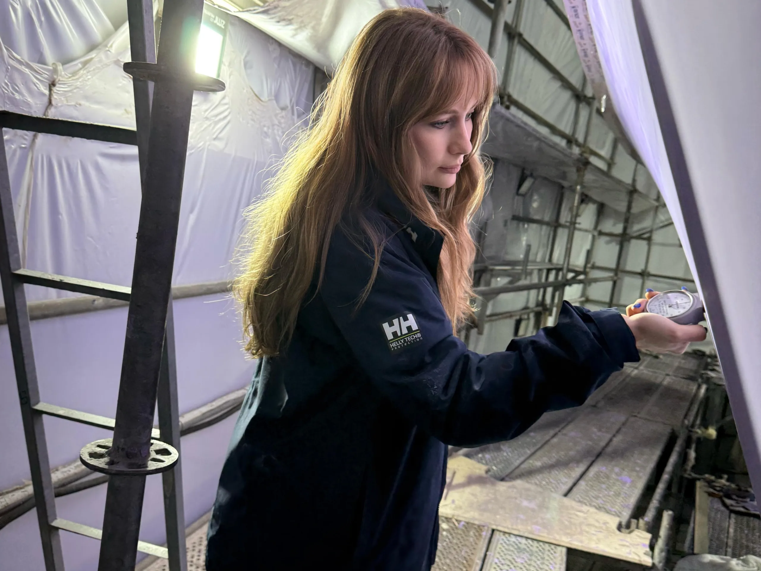 TECHNICIAN MEASURING CURED FAIRING COMPOUND (PUTTY) HARDNESS WITH A SHORE D DUROMETER DURING A YACHT REFIT.